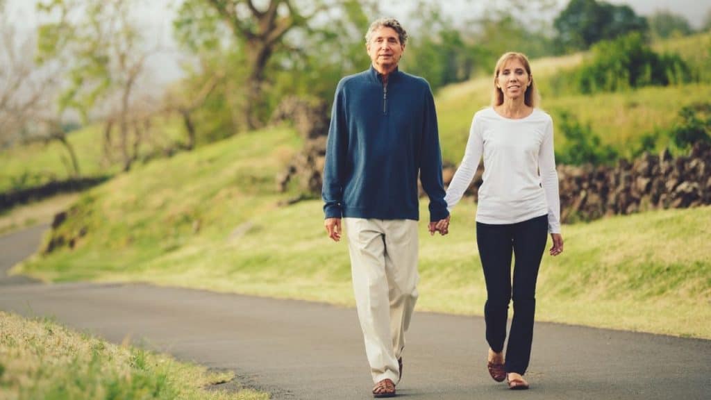 Couple casually dressed, holding hands, and comfortably taking a walk in the park.