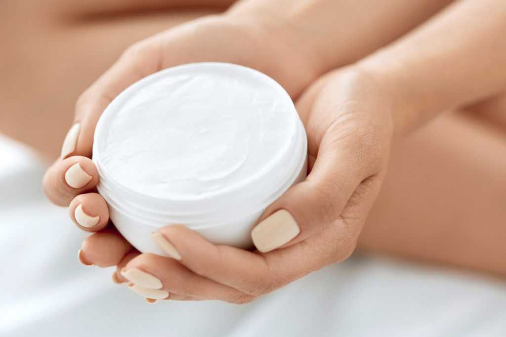A woman is holding a moisturizer.