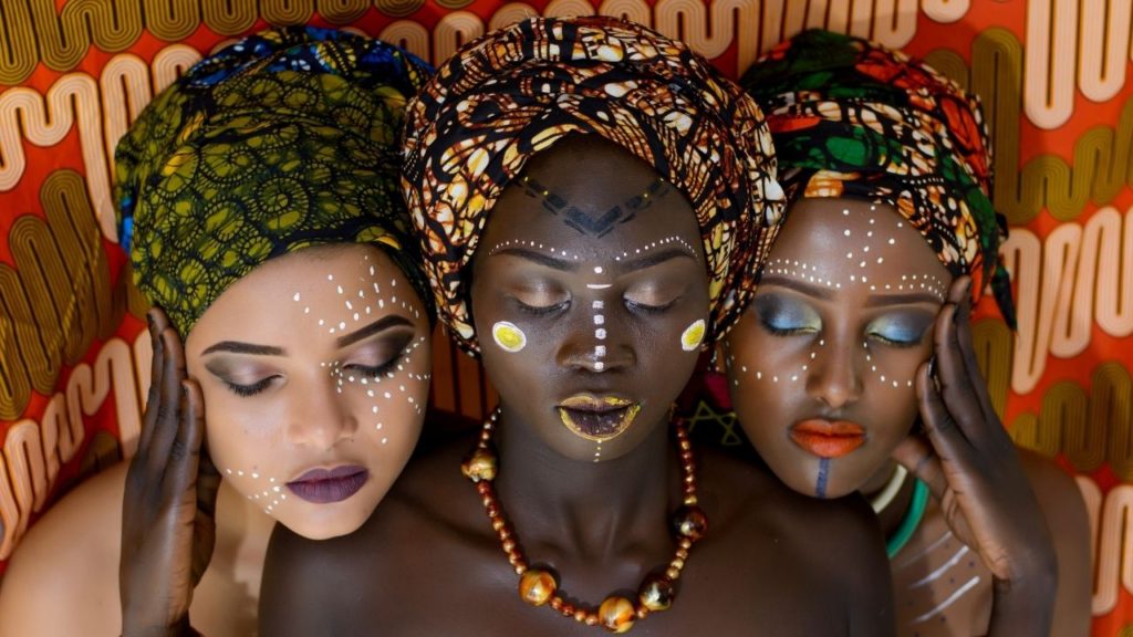 Three beautiful women are dressed in colorful costume and very beautiful makeup.