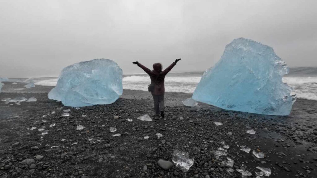 Person standing in between two big blocks of ice on Diamond Beach in Iceland