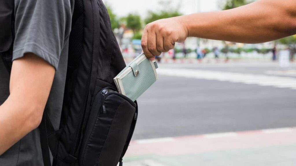 man pickpocketing a backpack - Scams to avoid in Europe