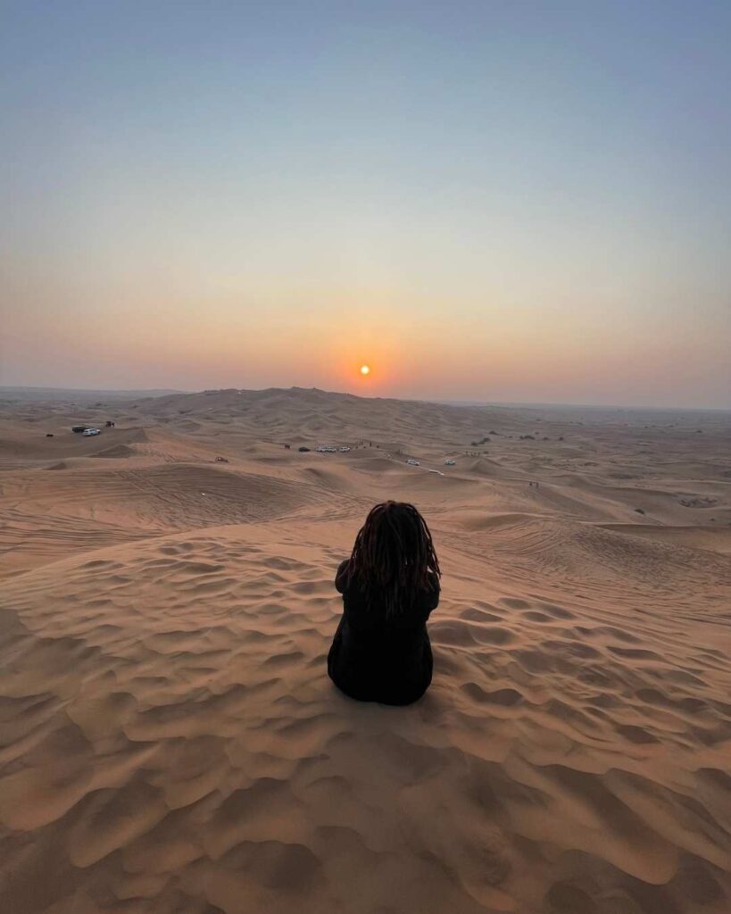 Kendra watching the sunset on a sand dune - things to do in Dubai