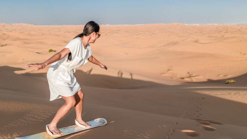 Woman in white dress sandboarding